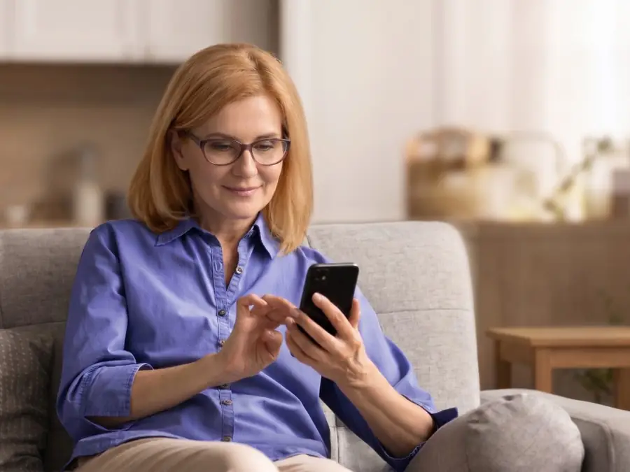 Kvinde i konsultation med lægen hjemme fra sofaen på sin telefon